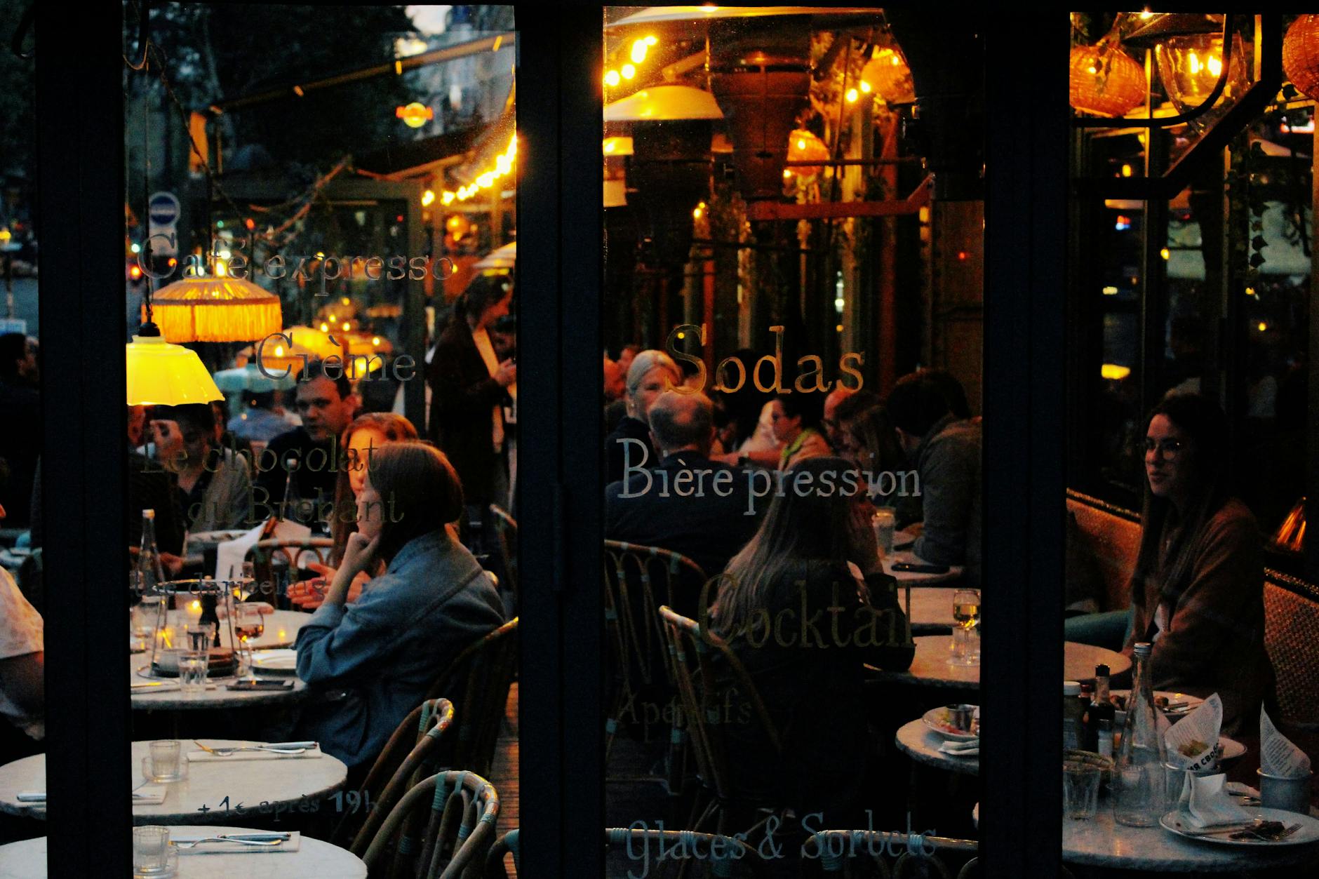 A vibrant café scene in Paris with people enjoying an evening at candlelit tables.