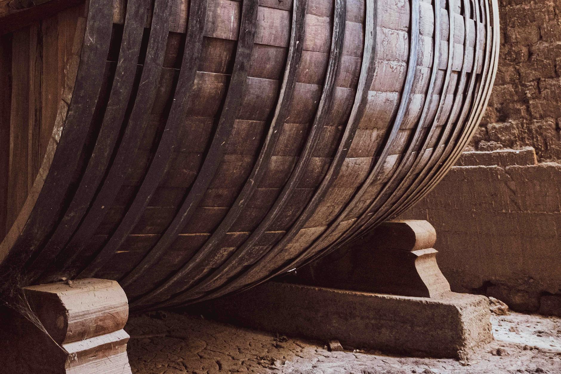 Close-up of a large wooden wine barrel in an ancient wine cellar, highlighting the historic architecture.