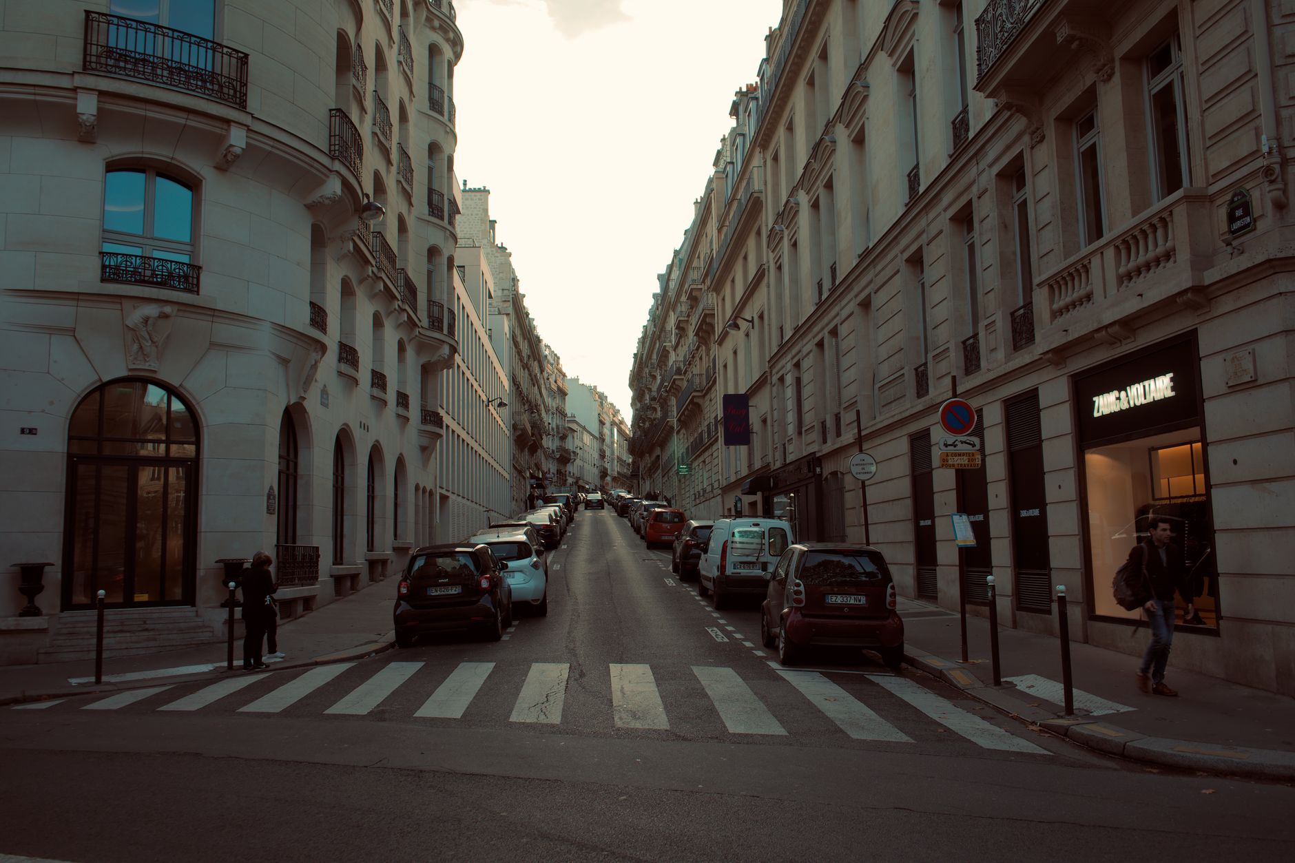 A picturesque European street lined with classic architecture and parked cars.