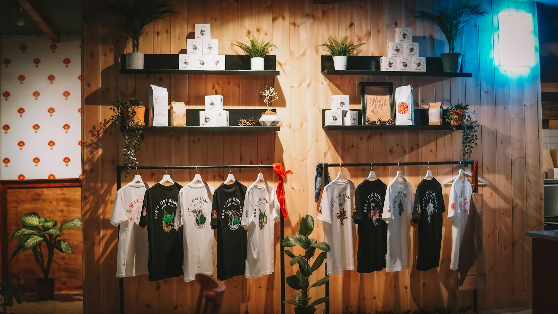 Stylish T-shirt display in a cozy, modern retail store with plants and wooden decor.