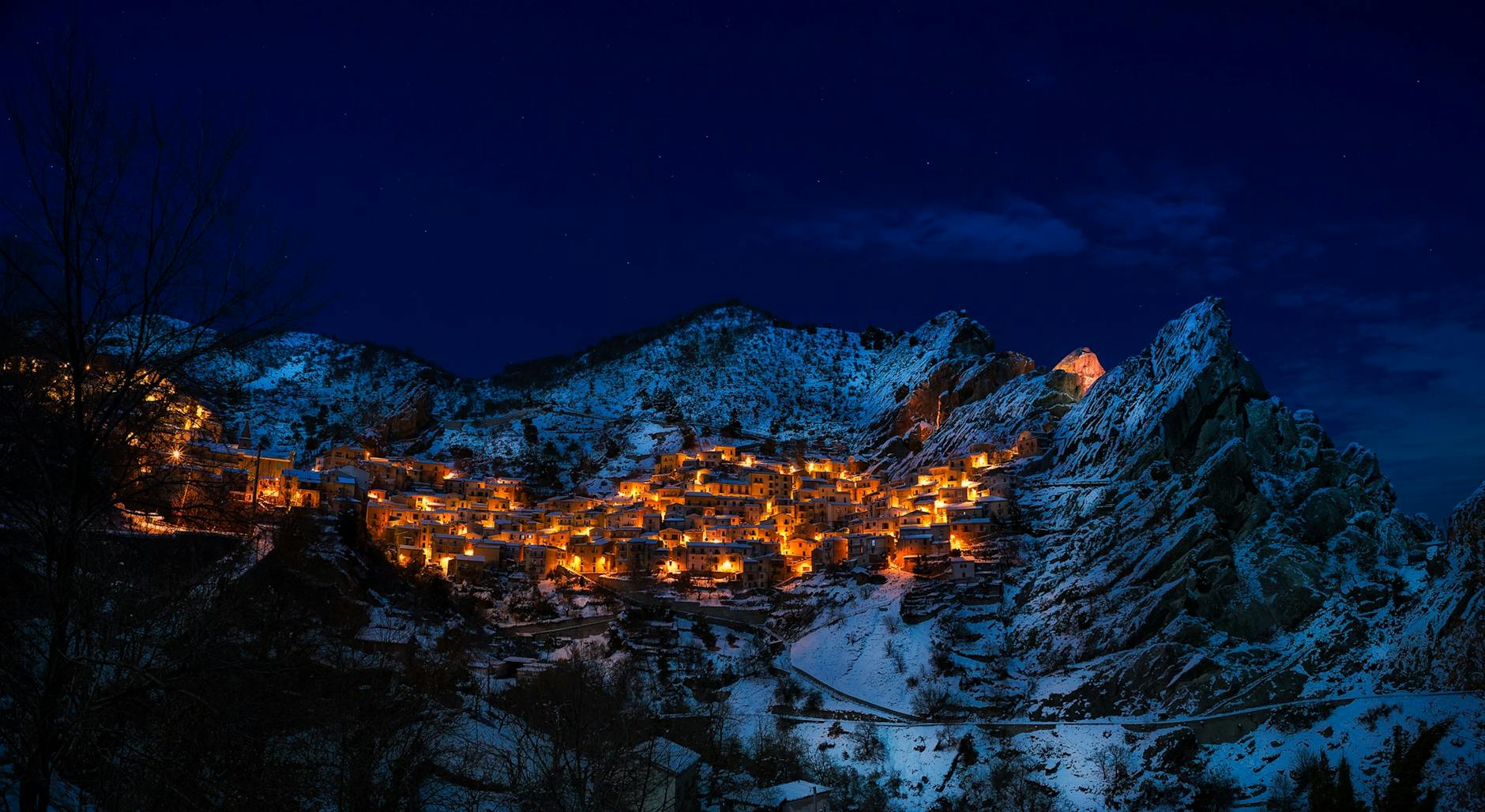 A captivating winter scene of a snow-covered mountain village illuminated at night.
