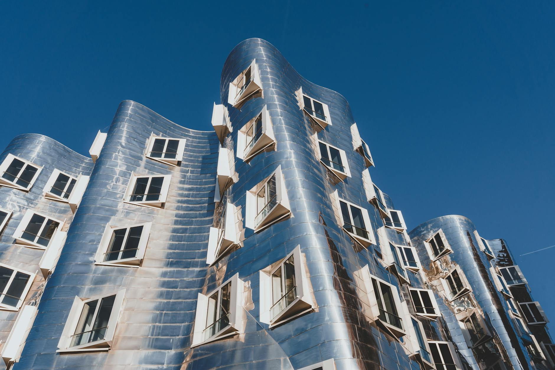 Explore the iconic modern design of Neuer Zollhof building against a bright blue sky in Düsseldorf, Germany.