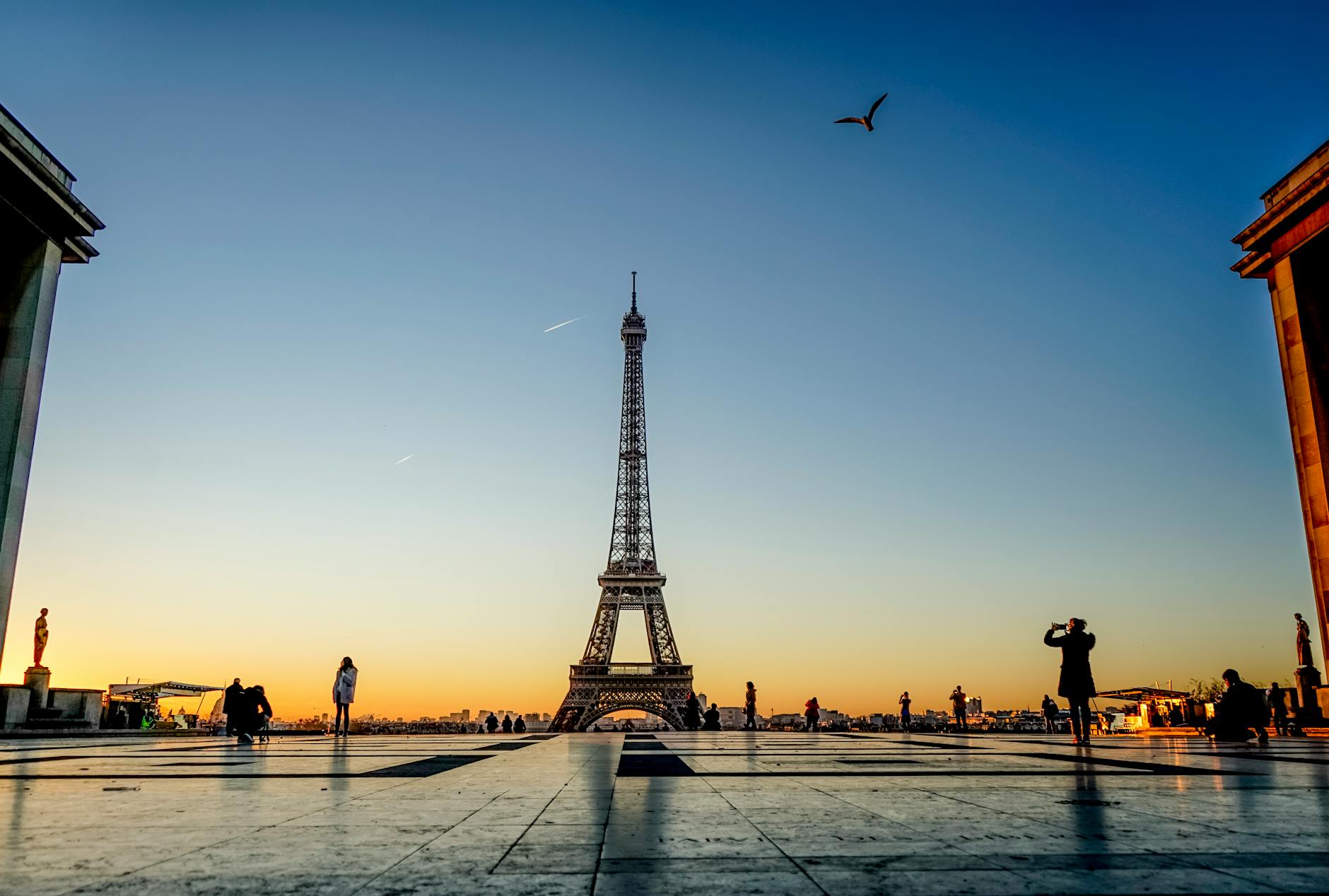 Capture of the Eiffel Tower at sunrise with silhouettes of people and birds in Paris, France.