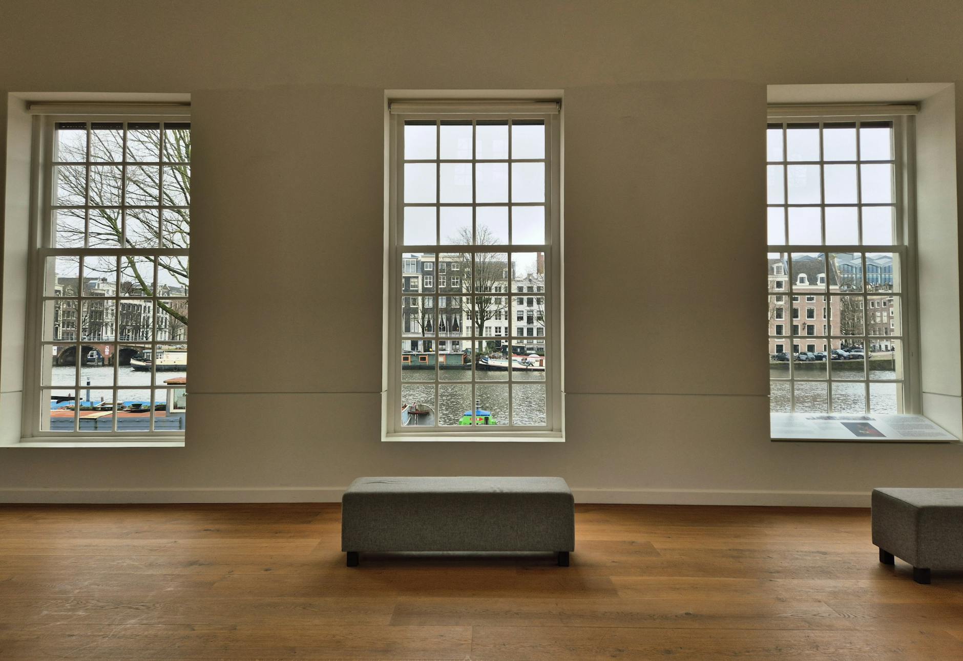 Gallery interior with large windows showcasing a scenic canal view, emphasizing architecture and tranquility.