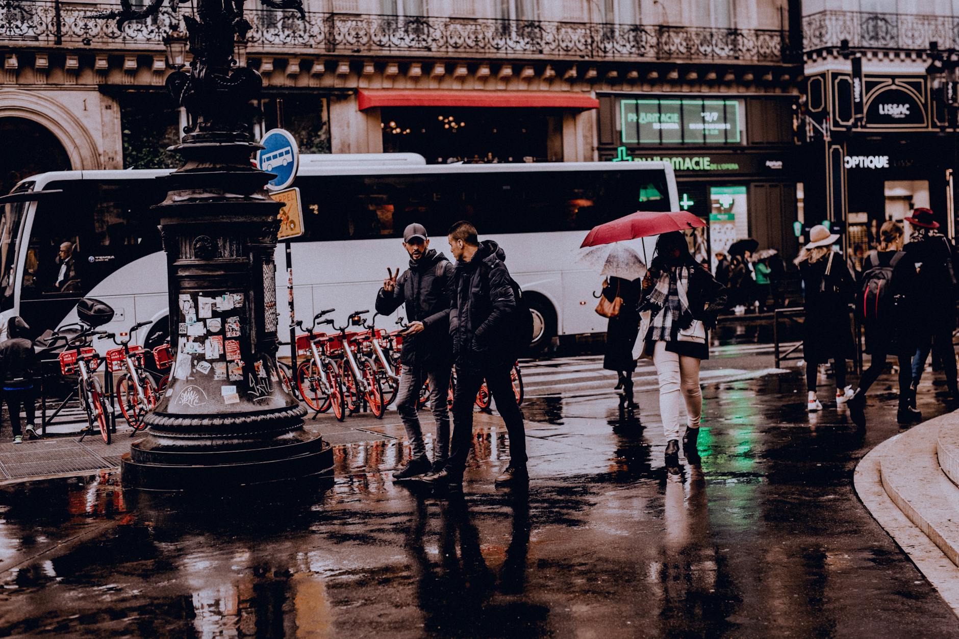 Street view of people with umbrellas walking on a rainy day, reflecting city life.