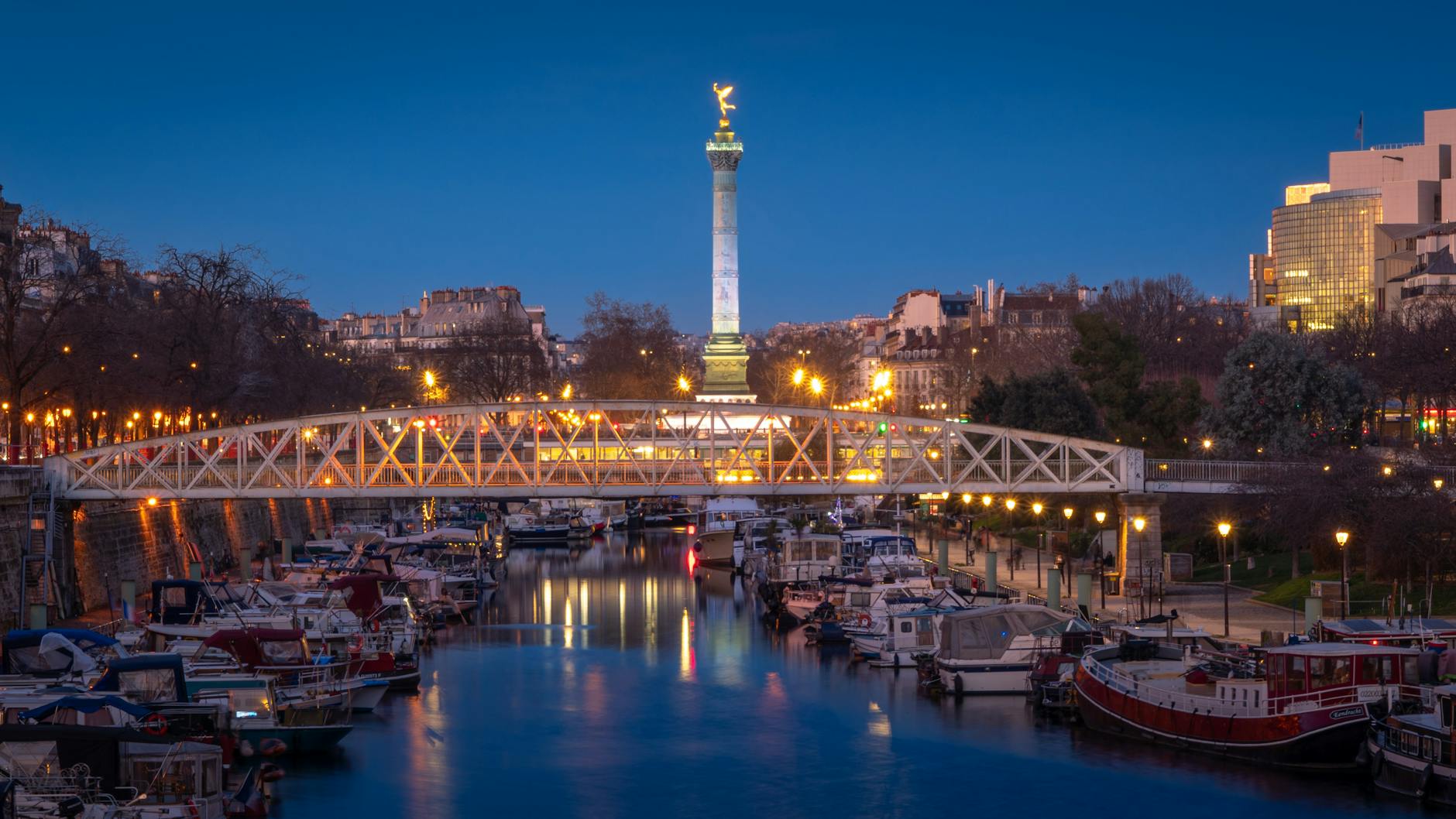 Scenic evening view of the Bastille Square and boats on Canal Saint-Martin in Paris, France.
