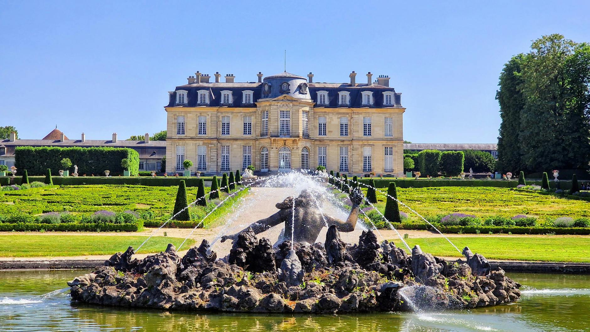 Explore the stunning gardens and architecture of Château de Champs-sur-Marne during a bright summer's day.