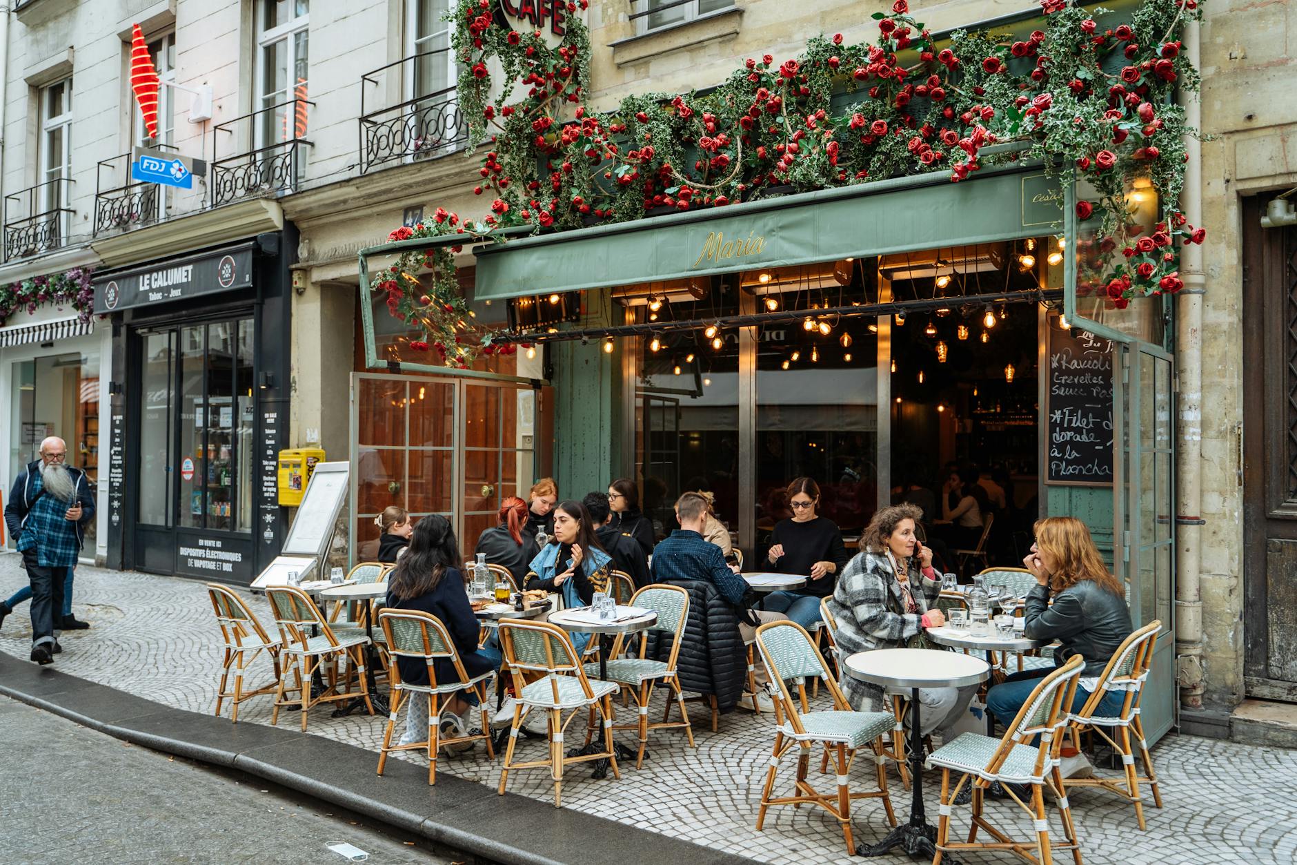 A lively street scene of a Parisian cafe with vibrant outdoor ambiance and dining.