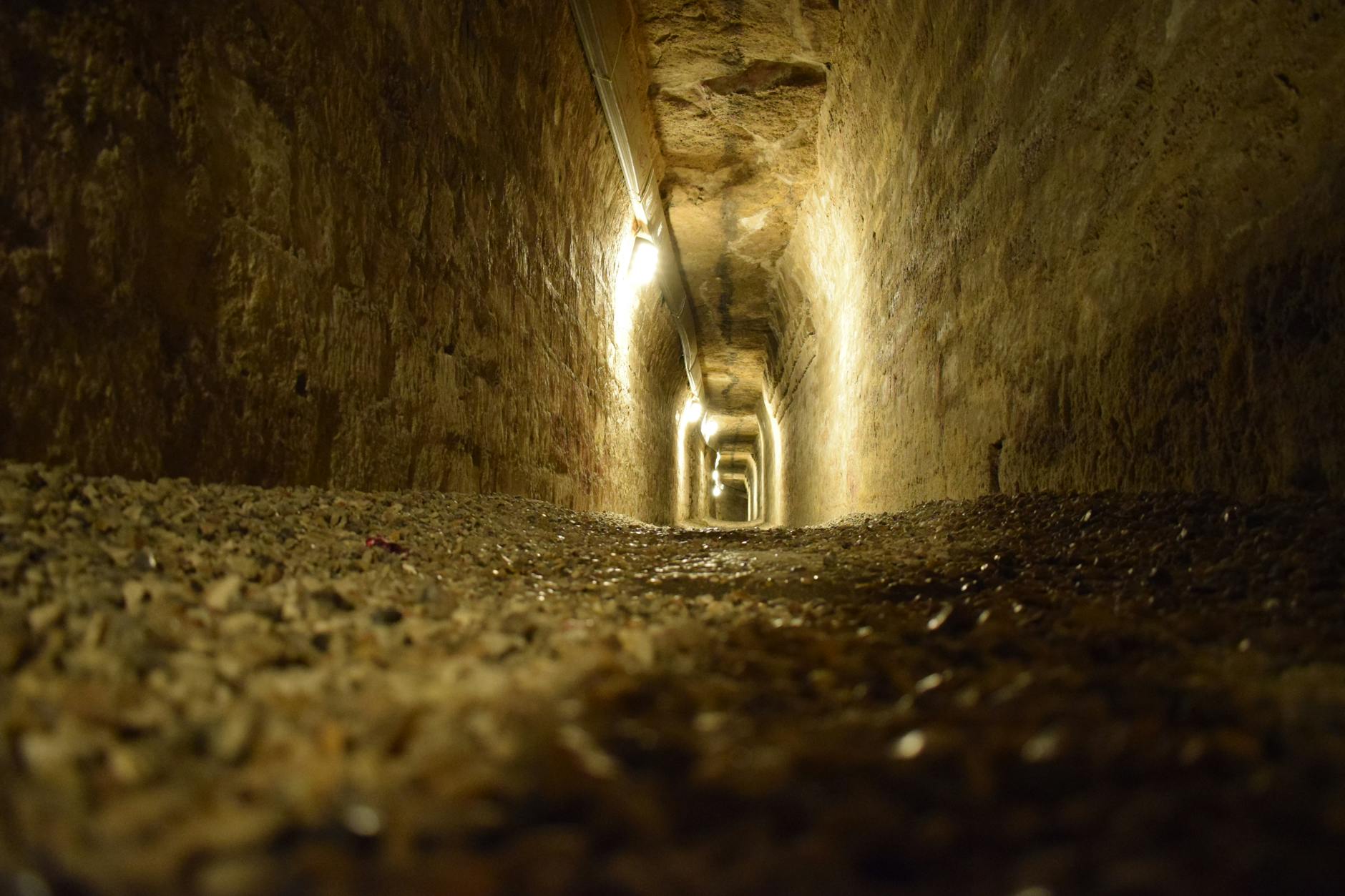 Moody stone tunnel in the Paris Catacombs, dimly lit and mysterious.