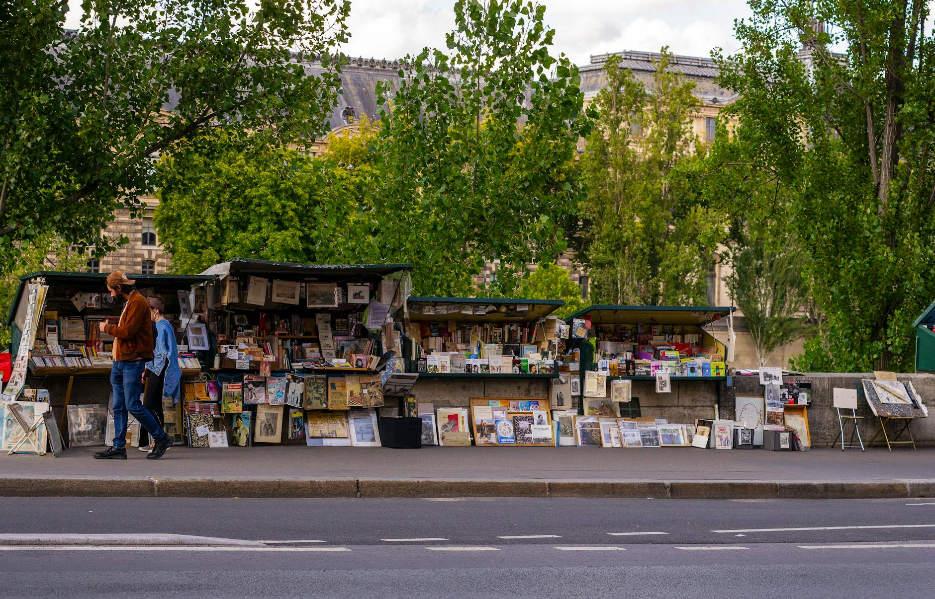Picturesque book stalls on a Paris street with people exploring in daylight.