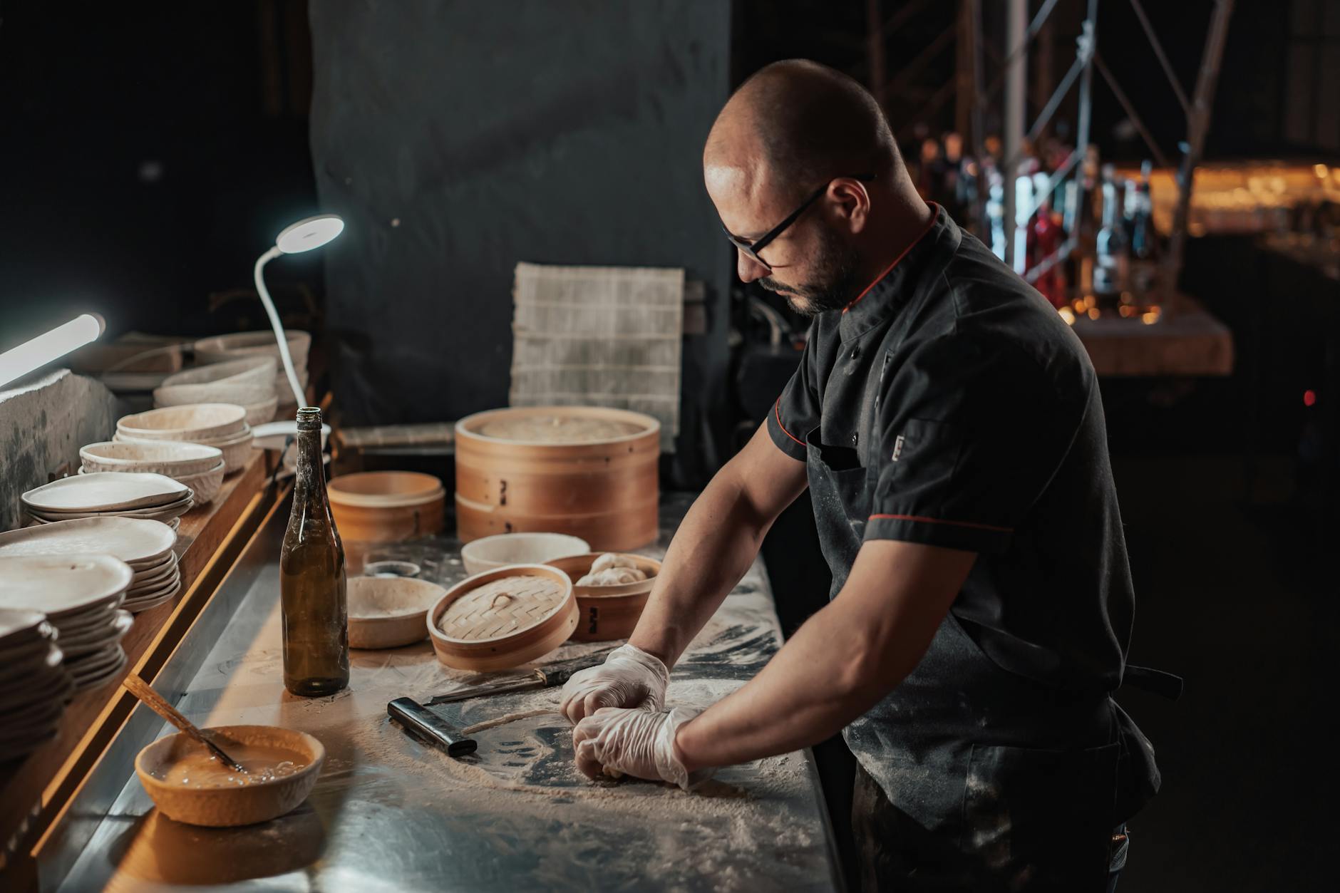 Chef preparing dumplings on a countertop with bamboo steamers in an indoor kitchen setting.