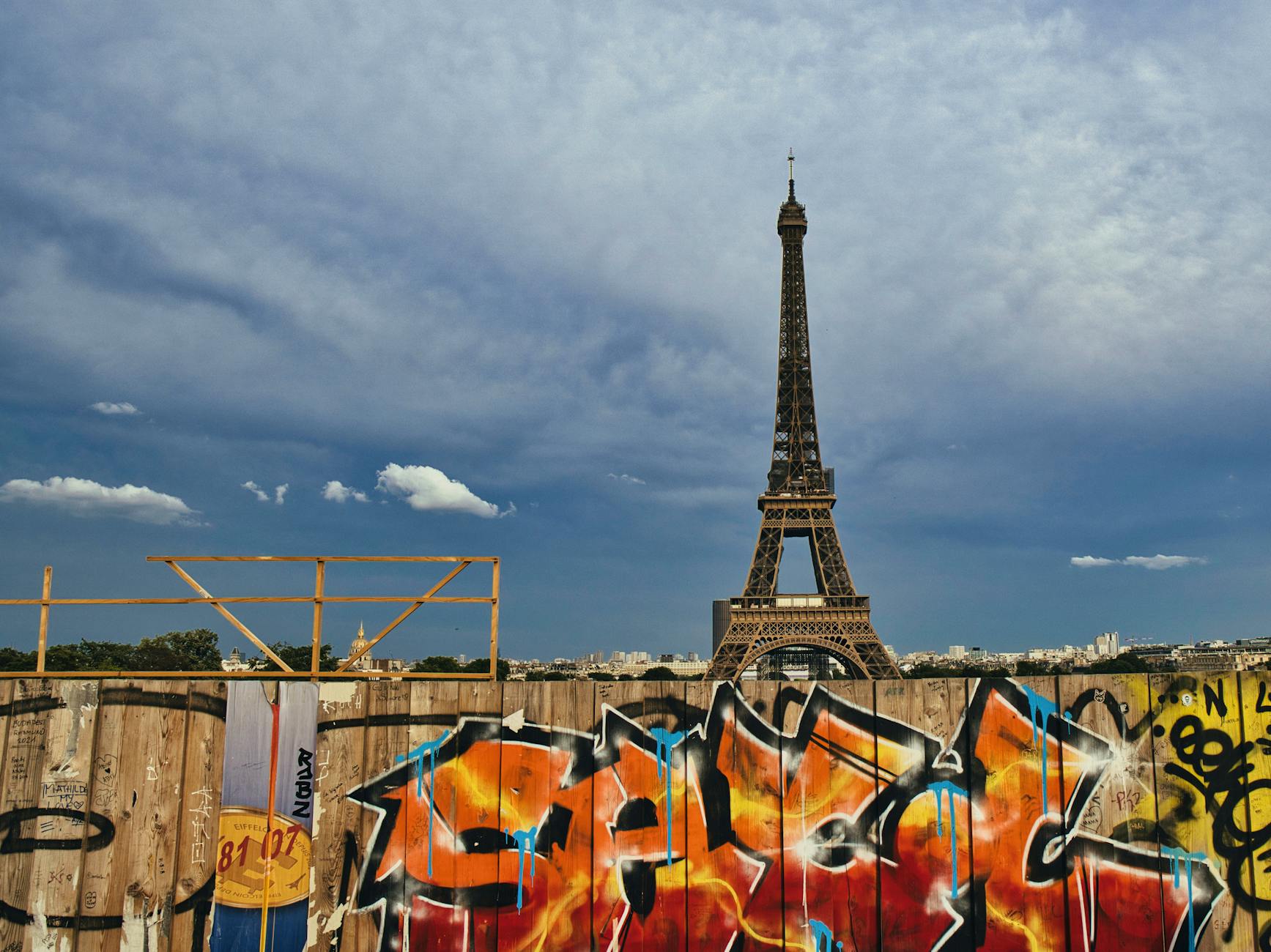 The Eiffel Tower rises behind vibrant graffiti, capturing urban Parisian art under a clear sky.