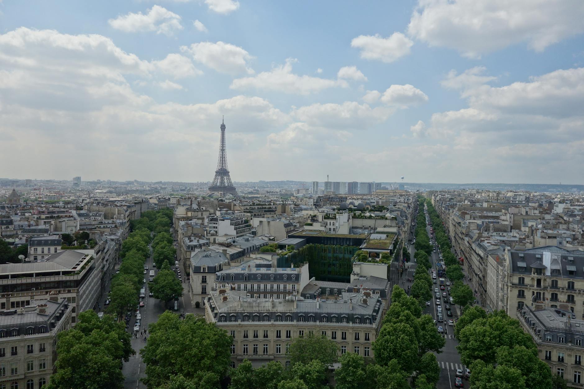 Stunning aerial view of Paris featuring the iconic Eiffel Tower under a cloudy sky.