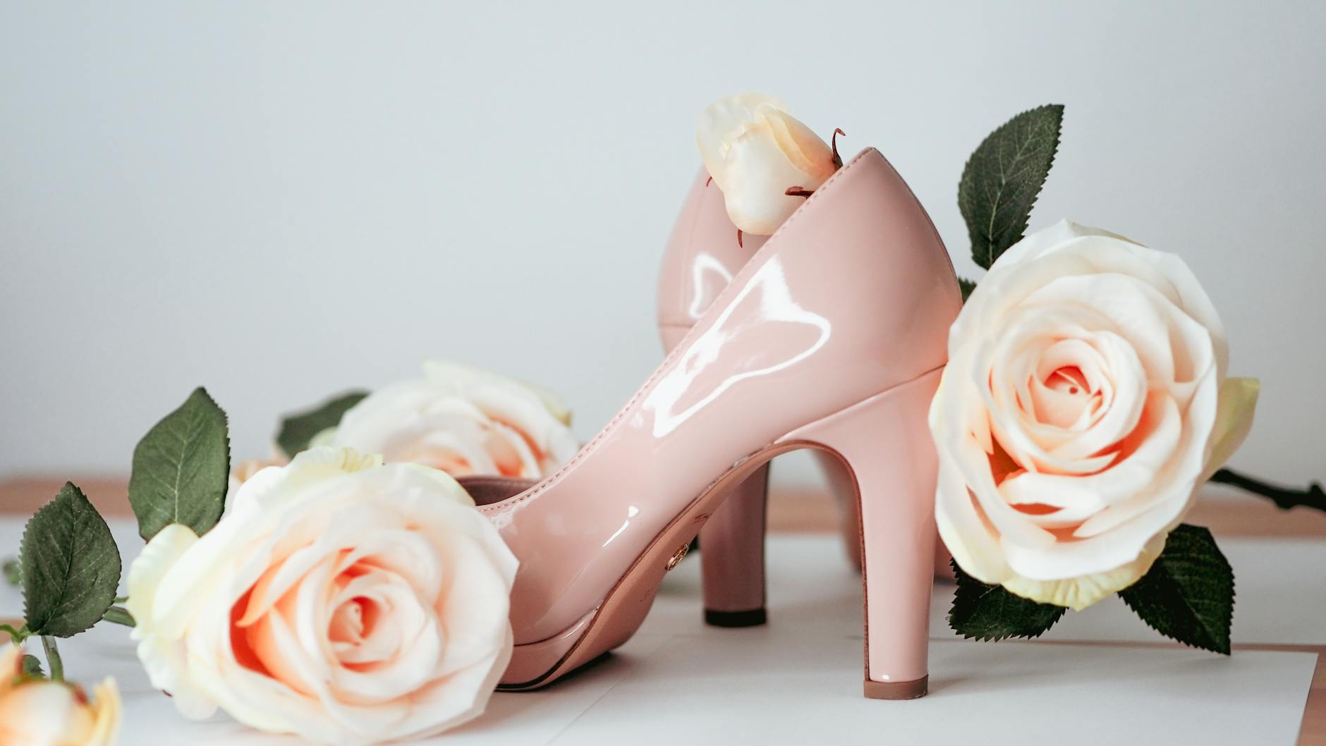 Stylish pink high heels surrounded by delicate roses in an elegant arrangement, perfect for fashion and beauty themes.