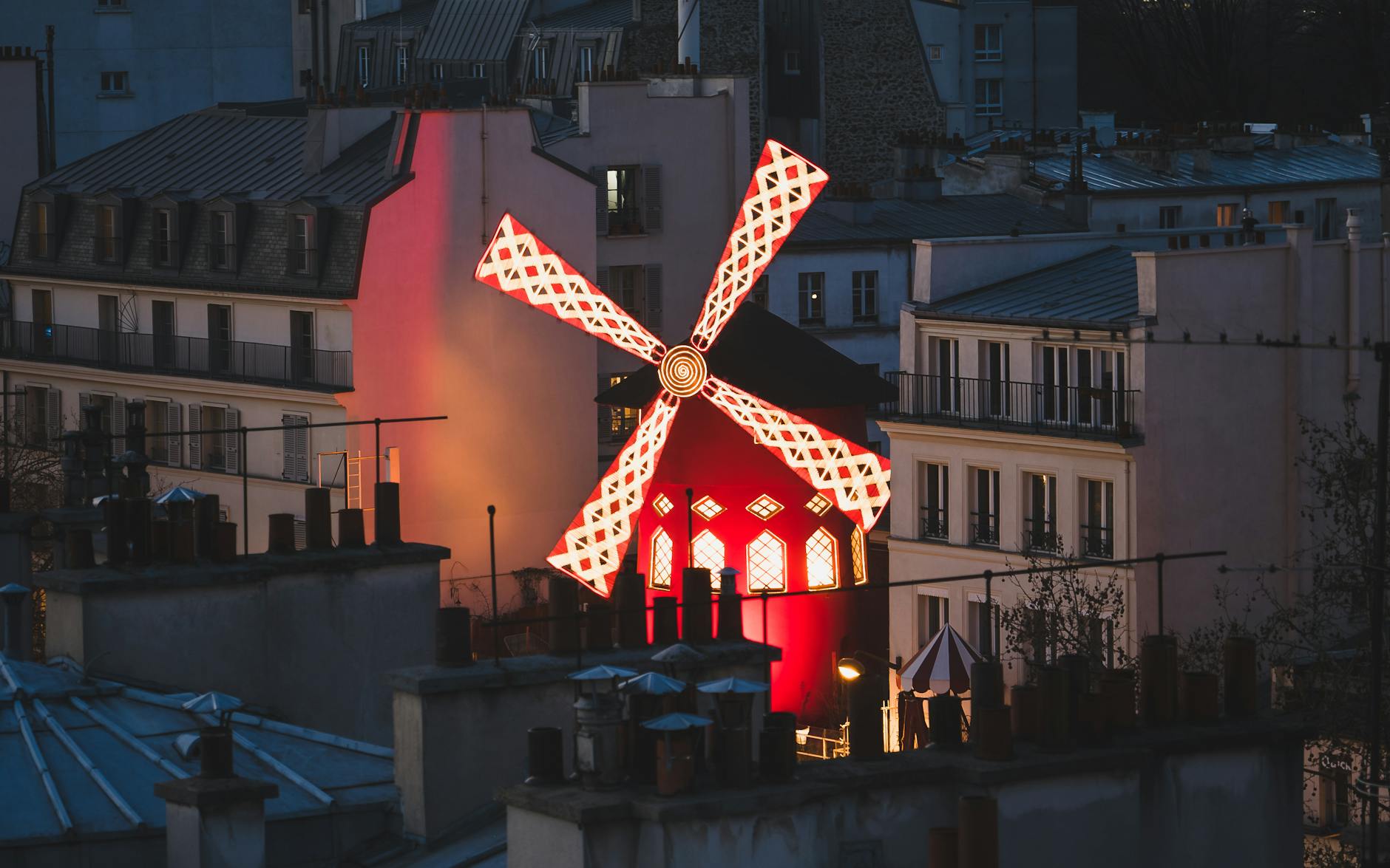 Evening view of the iconic red windmill at Moulin Rouge, a landmark of Parisian nightlife.