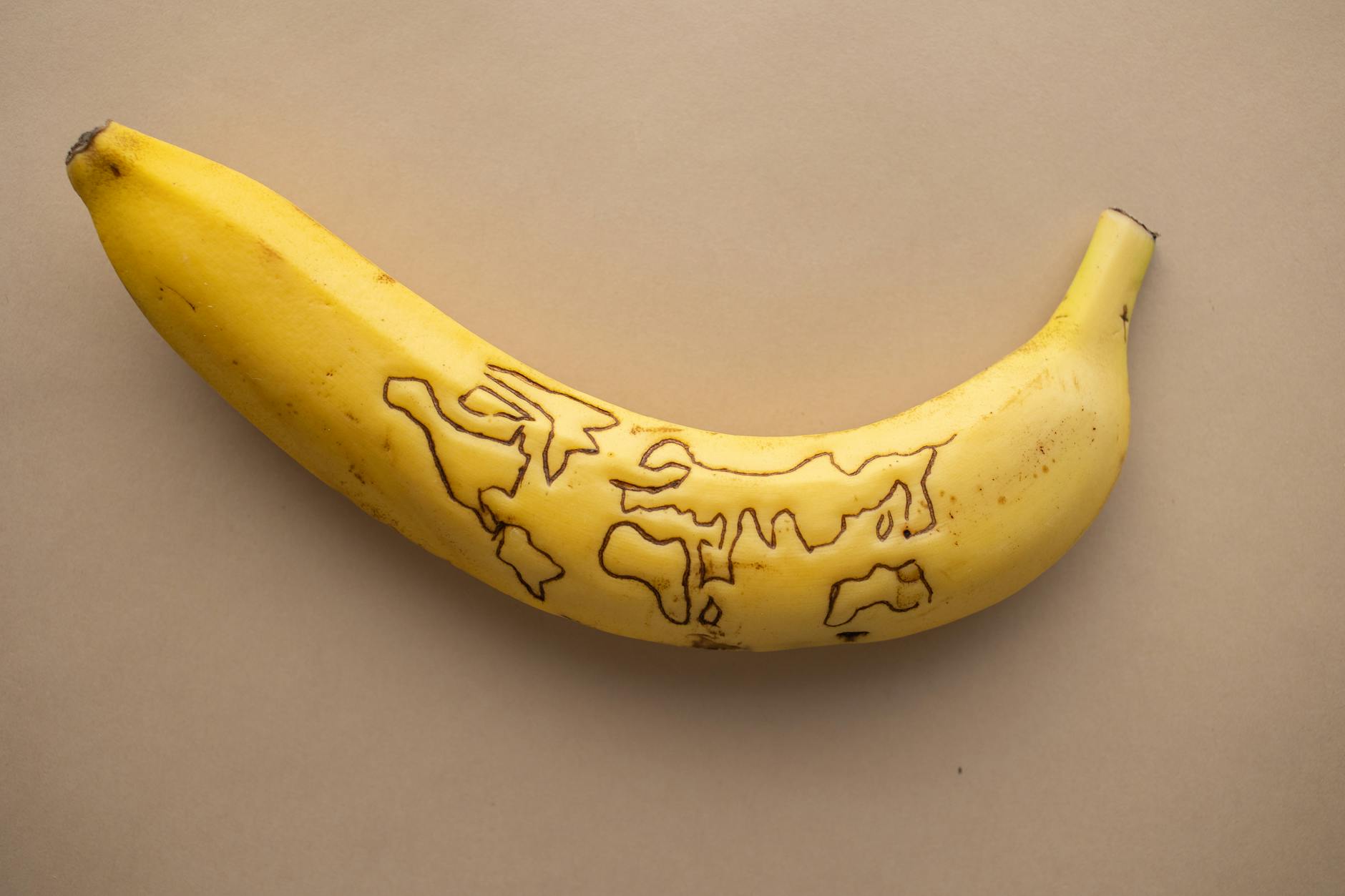 A close-up of a yellow banana with artistic doodles on a brown background. Perfect for creative food concepts.
