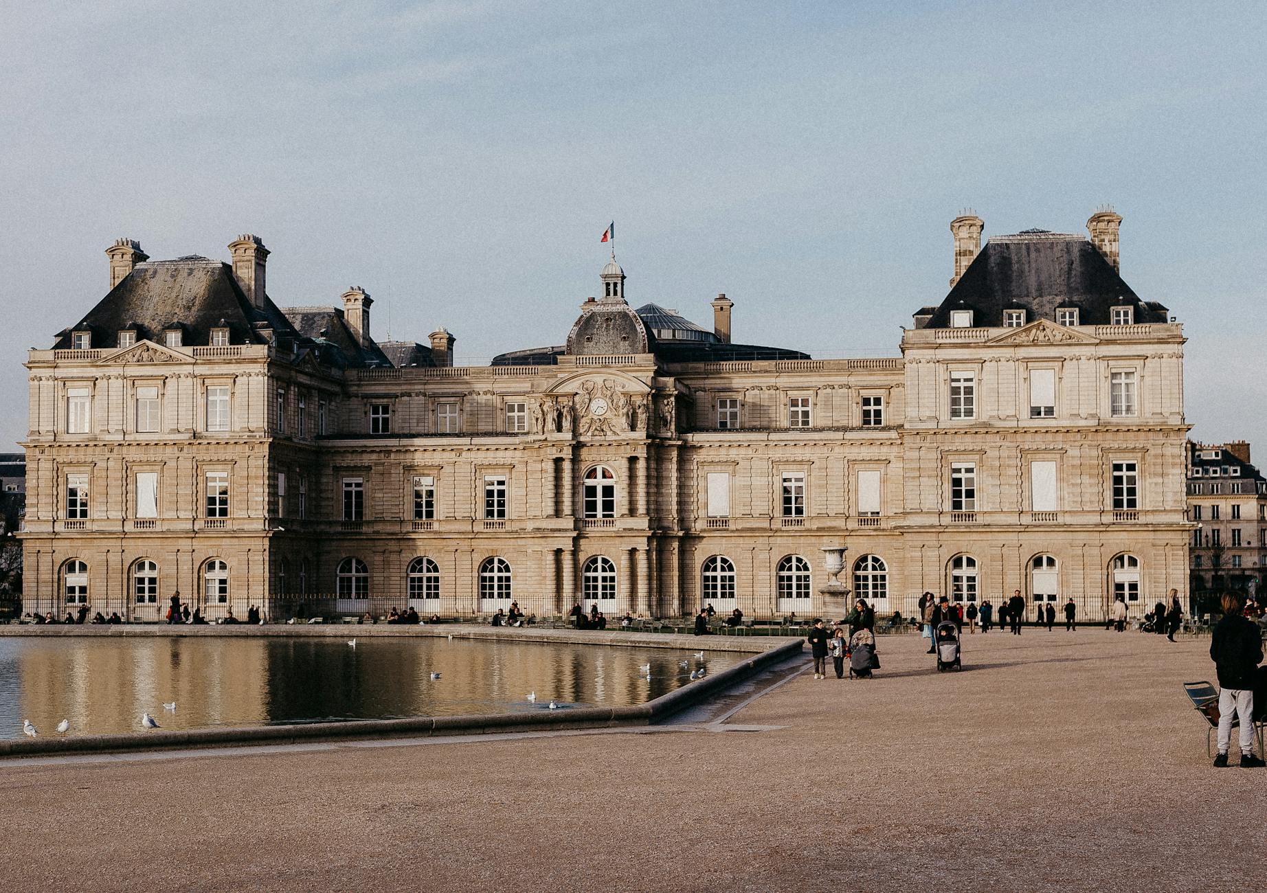 Luxembourg Palace reflecting in the water during daylight in Paris, France. Historic architecture, scenic view.