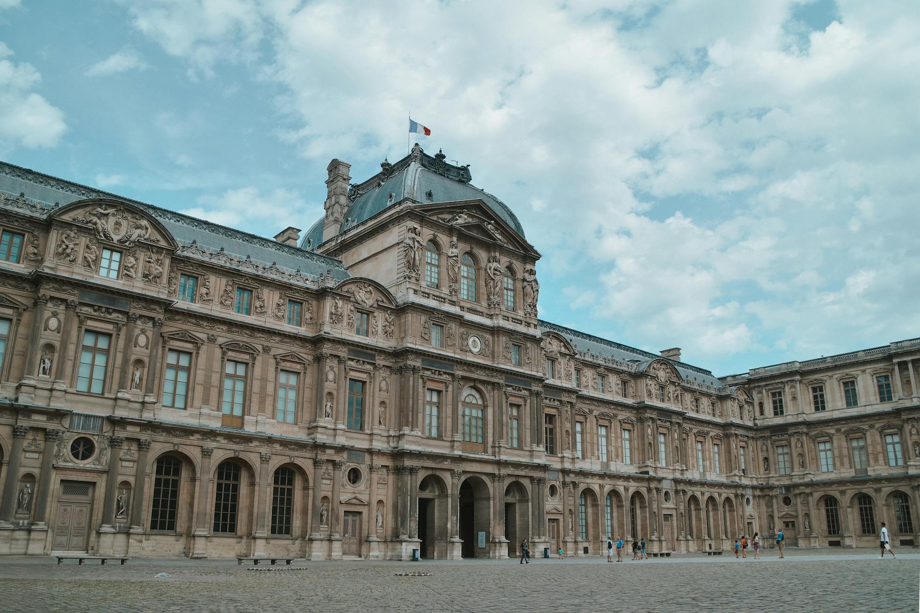 Facade of the Louvre Museum in Paris, showcasing stunning architecture under a bright sky.