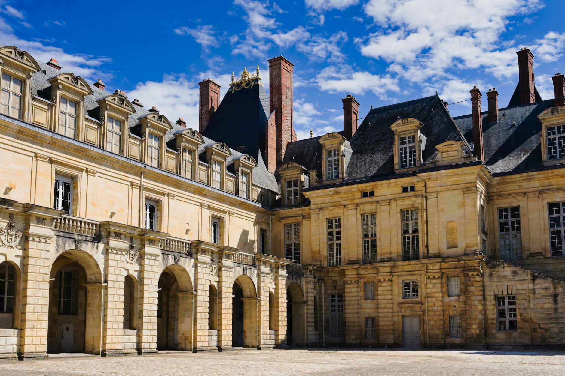 Stunning view of the Château de Fontainebleau under a vibrant blue sky, showcasing its historic architecture.