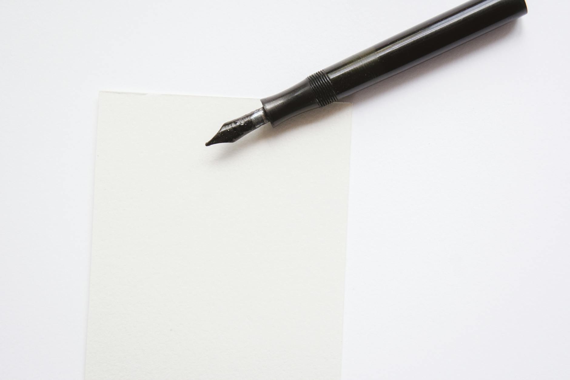 A close-up image of an elegant fountain pen resting on blank white paper, perfect for writing themes.