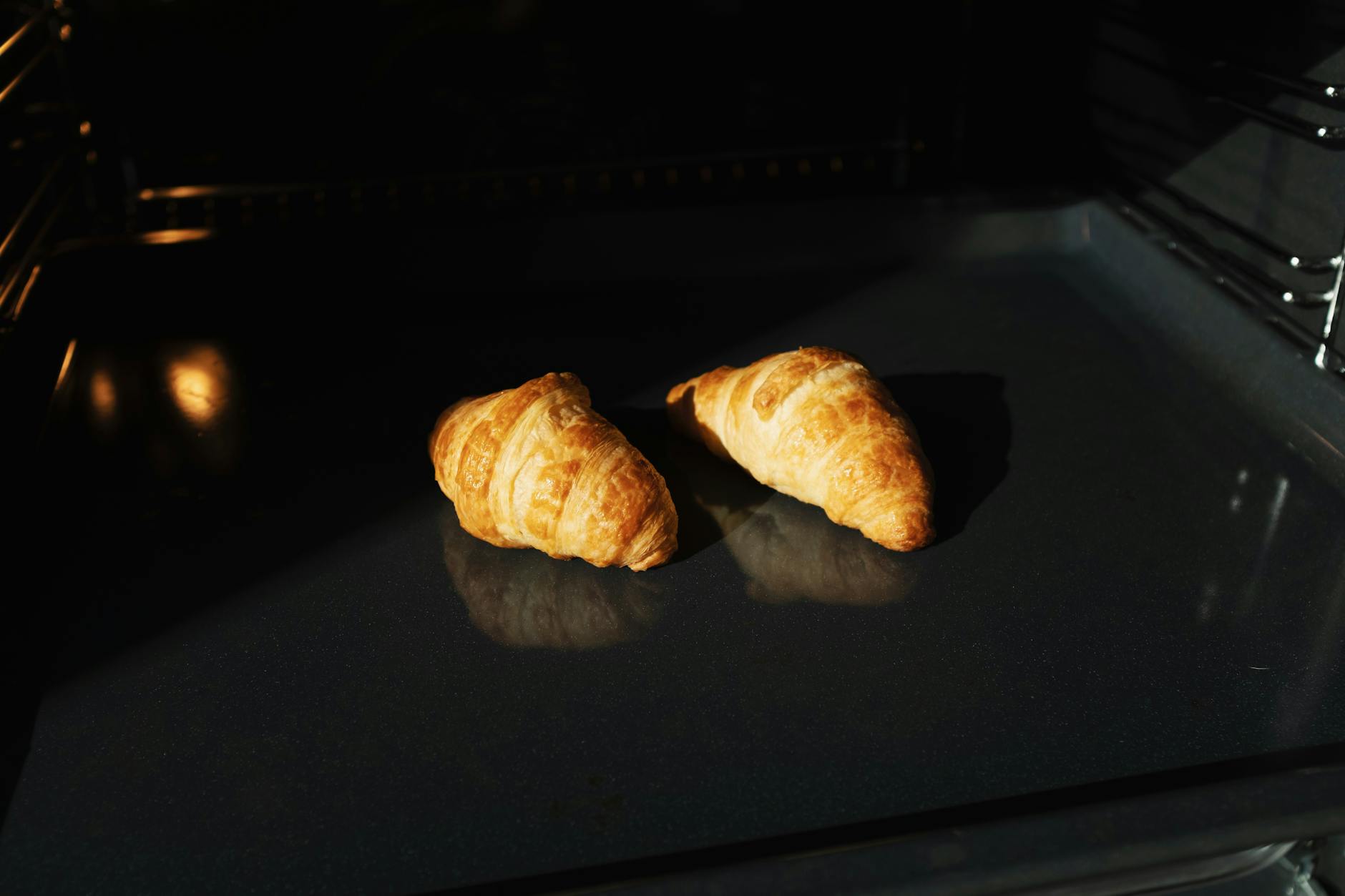 Freshly baked croissants in an oven, showcasing their golden texture and delicious appeal.