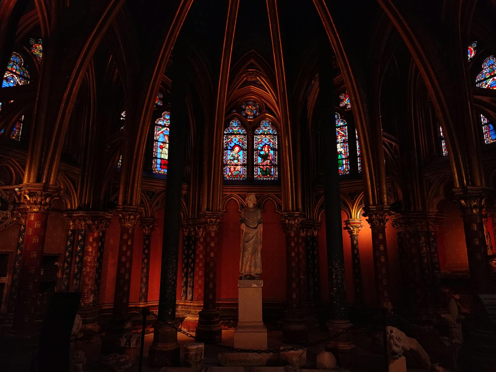 Gothic interior of Sainte-Chapelle in Paris with vibrant stained glass windows and sculptures.