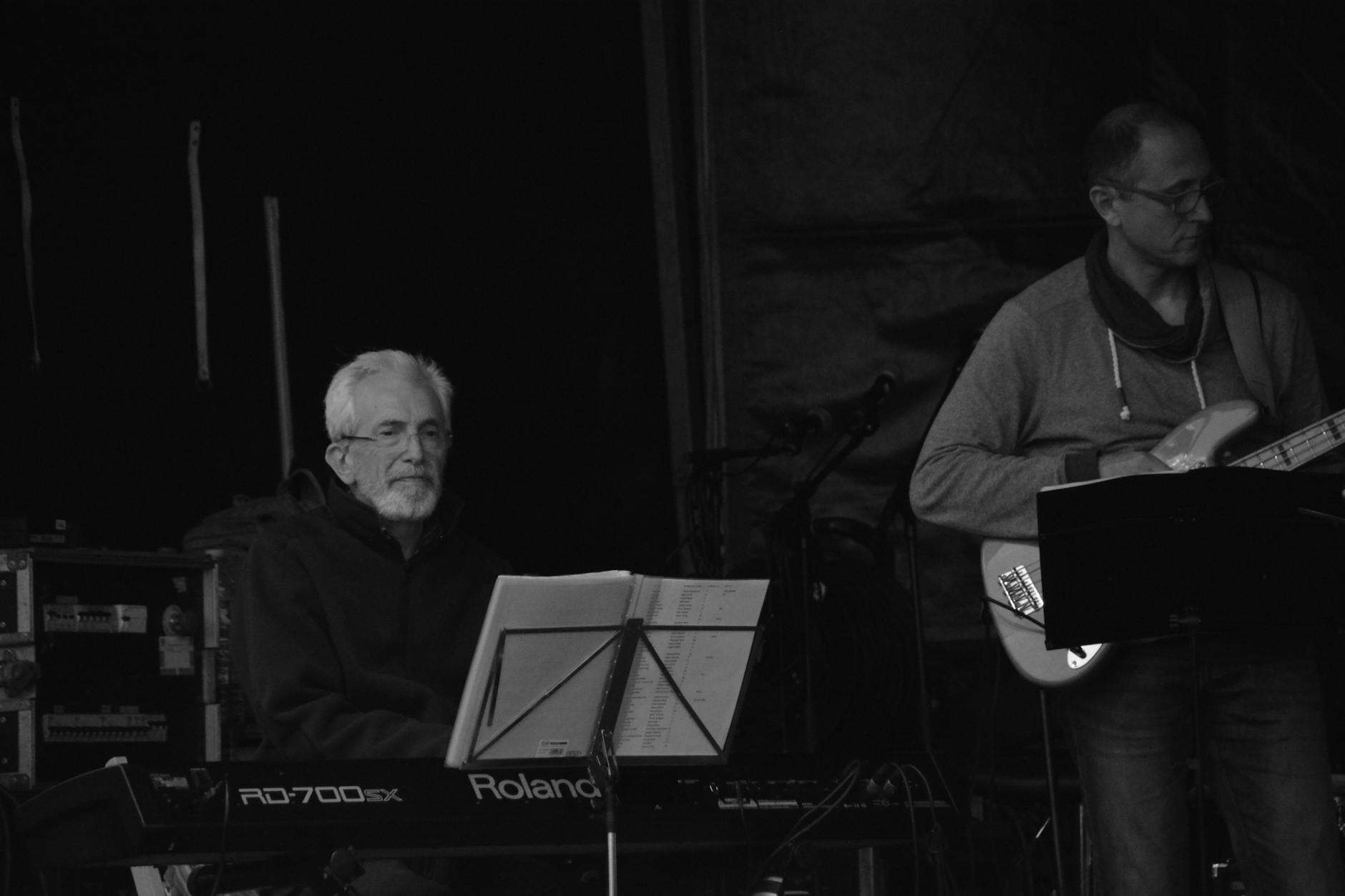 Jazz musicians performing with piano and guitar in a moody stage setting.