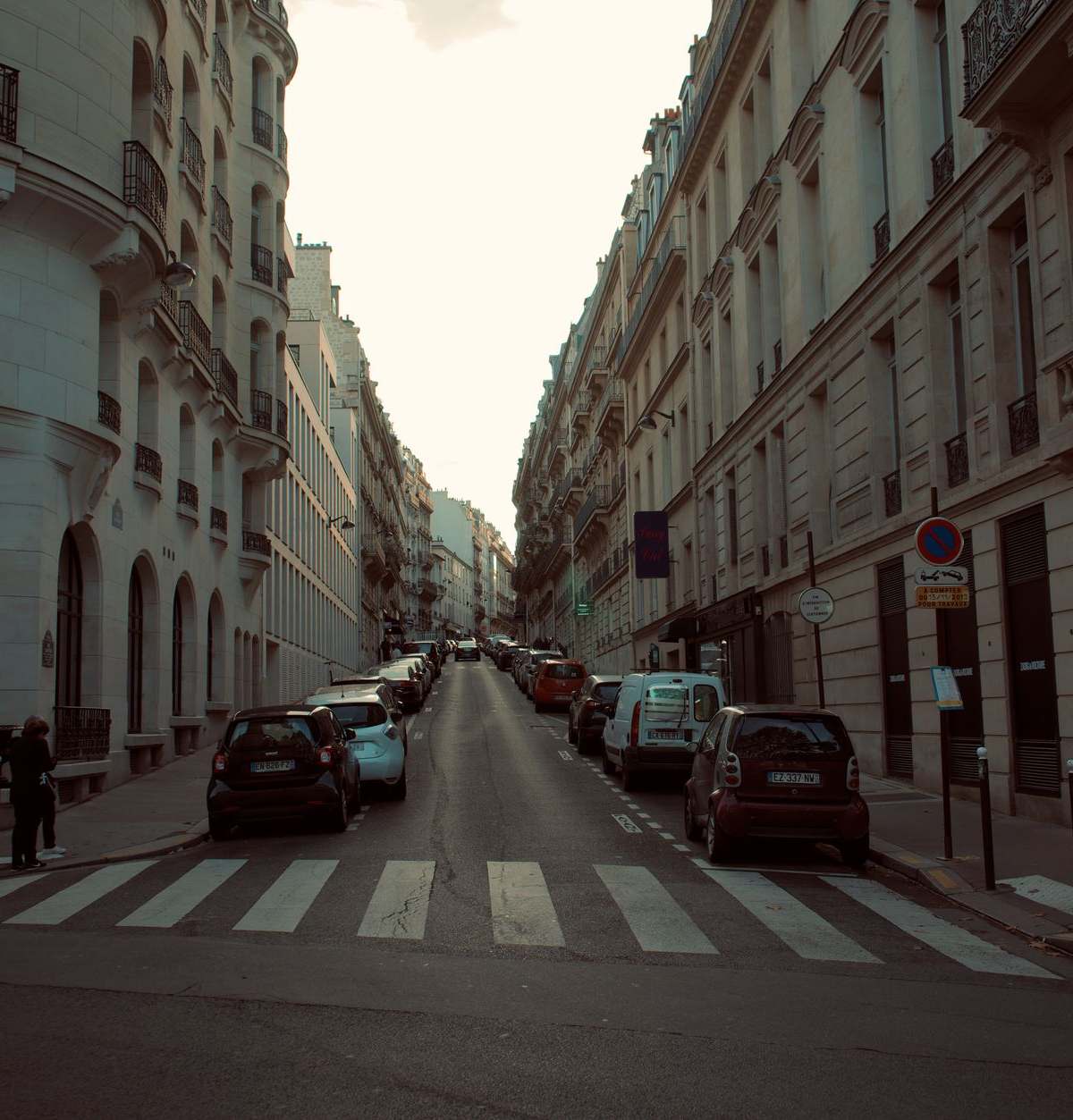 A picturesque European street lined with classic architecture and parked cars.