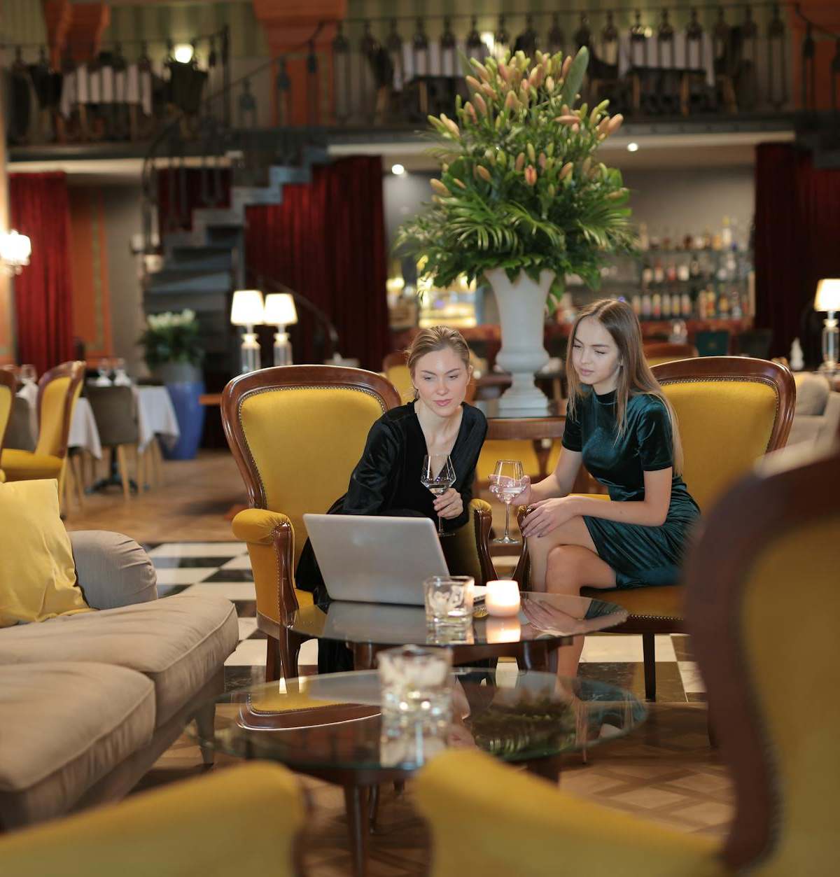 Two women enjoying a conversation in a luxurious hotel lounge, surrounded by elegant decor.