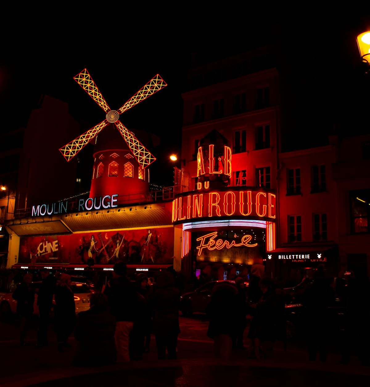 Illuminated night scene of the iconic Moulin Rouge in Paris, featuring its famous red windmill.
