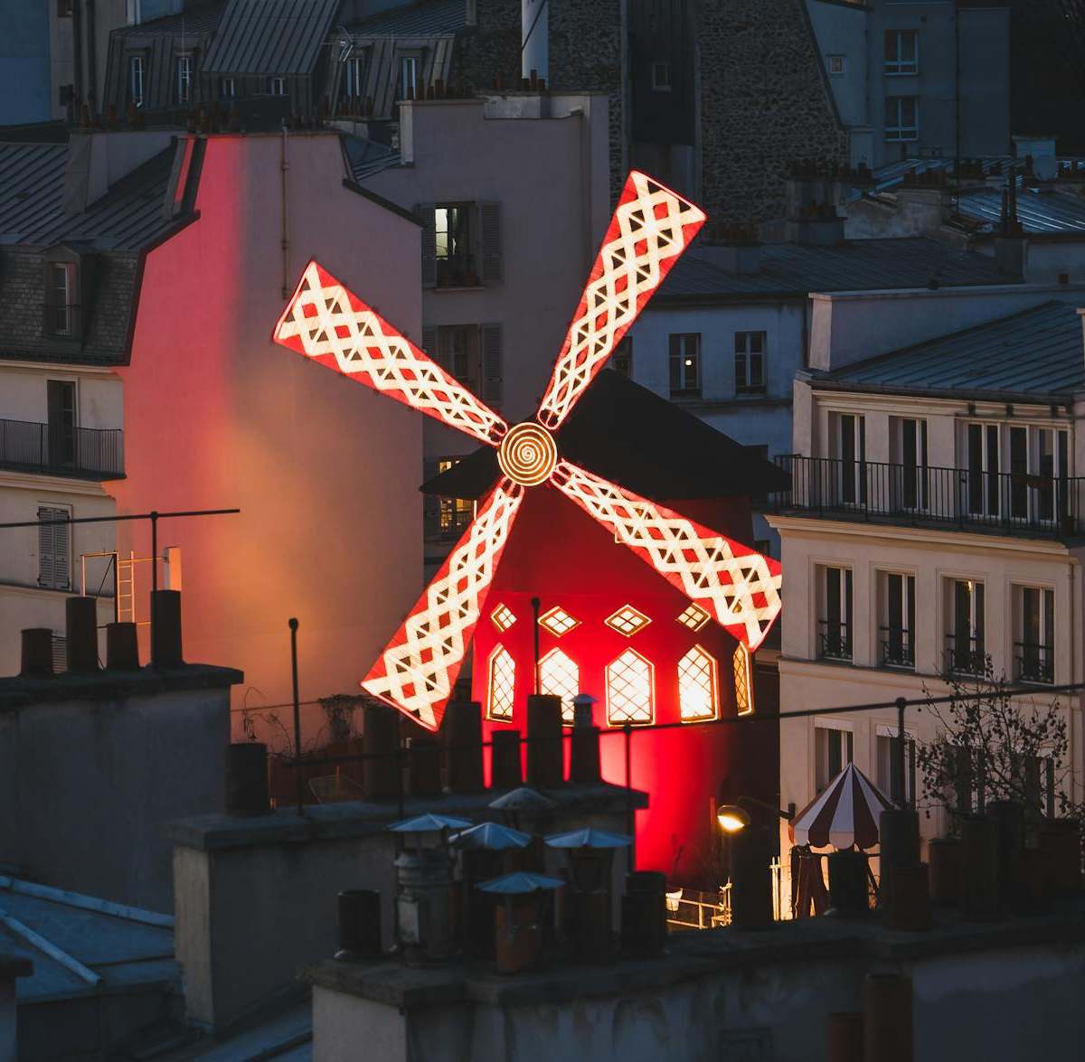 Evening view of the iconic red windmill at Moulin Rouge, a landmark of Parisian nightlife.