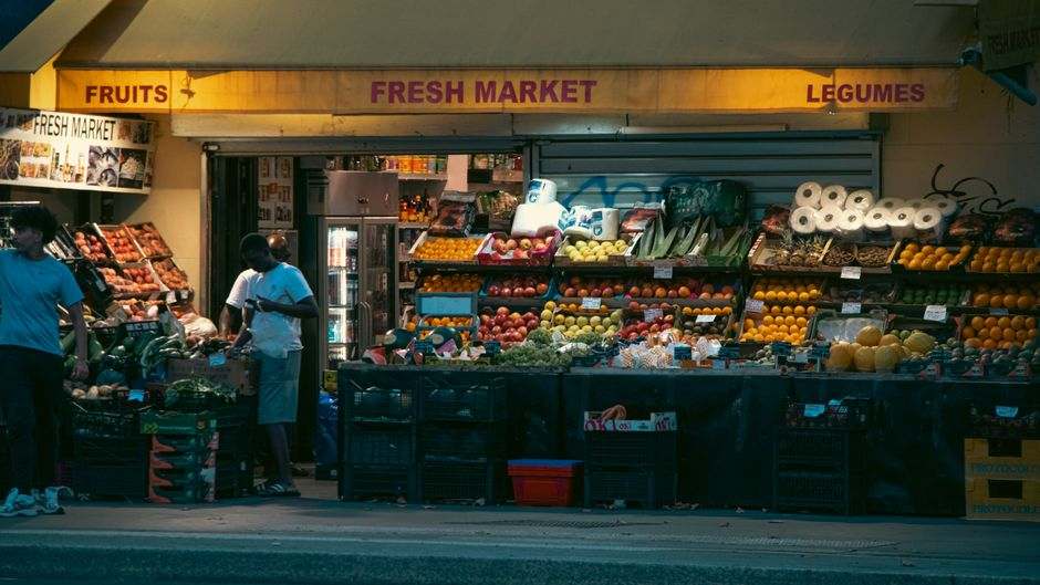 Night view of a fresh market in Paris displaying a variety of fruits and vegetables.