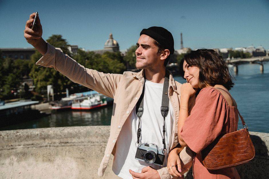 A couple taking a photograph on a Paris bridge
