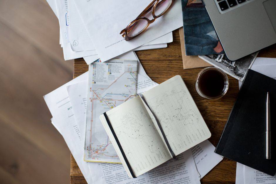 Maps, notes and a laptop on a travel-planning desk, illustrative photograph