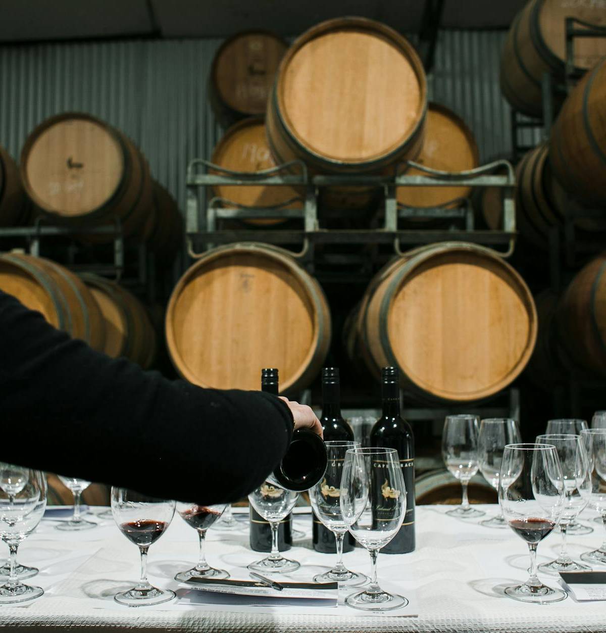 Wine poured for a tasting beside oak barrels, illustrative photograph