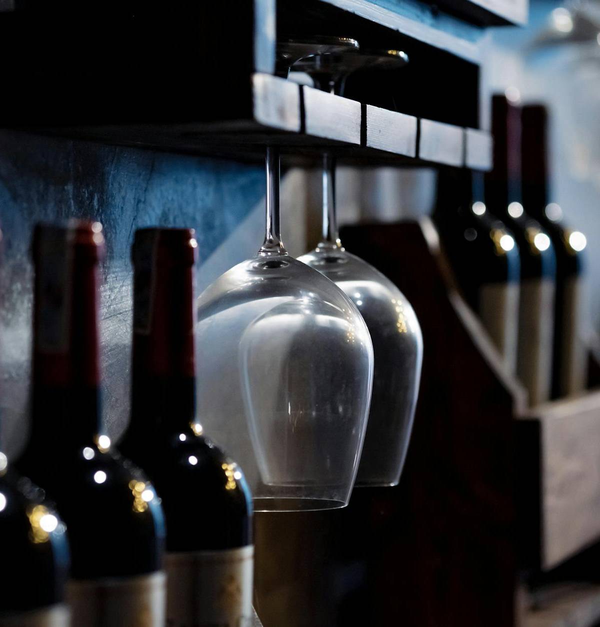 Wine bottles and glasses in a cellar, illustrative photograph