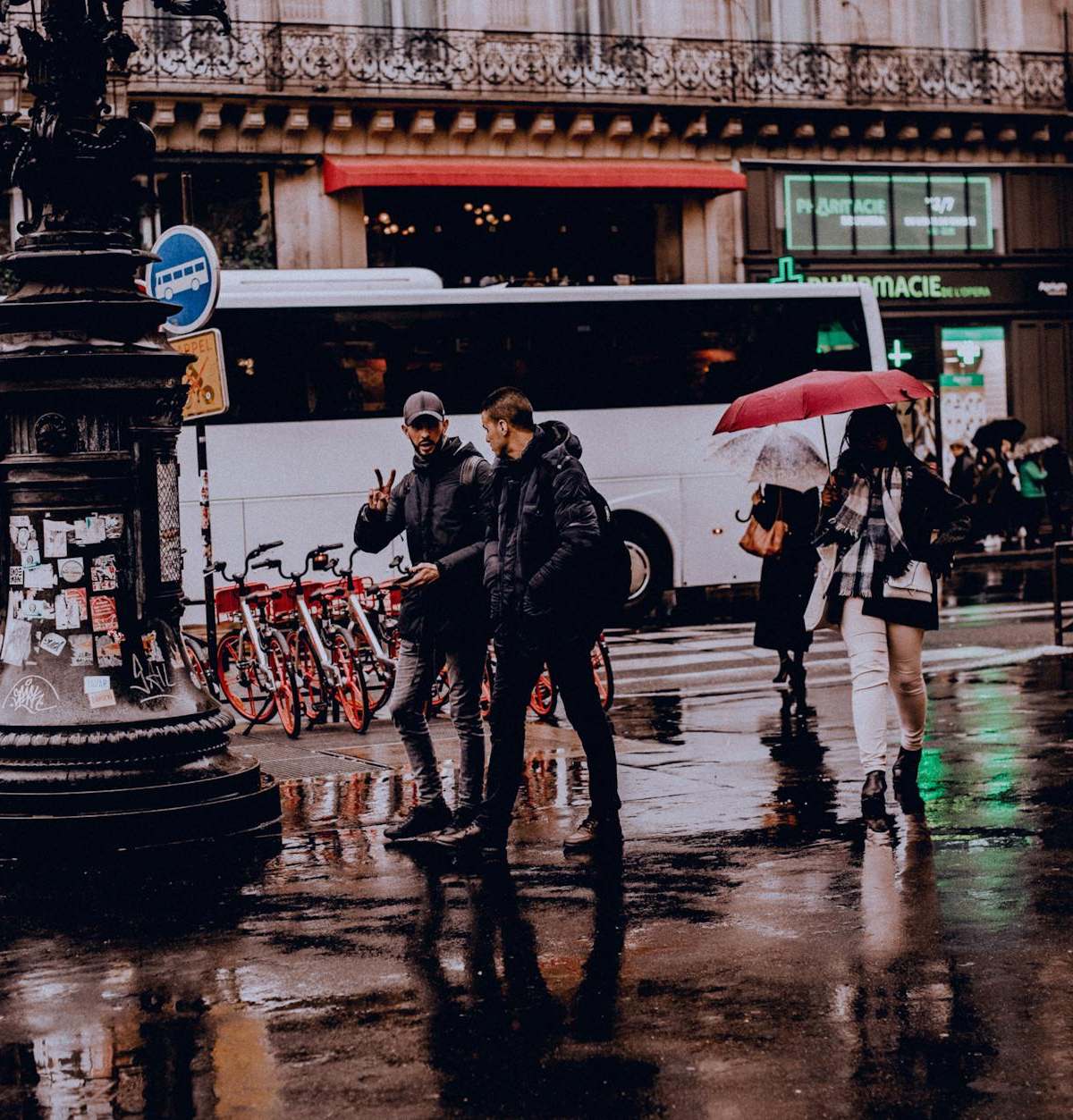 Street view of people with umbrellas walking on a rainy day, reflecting city life.