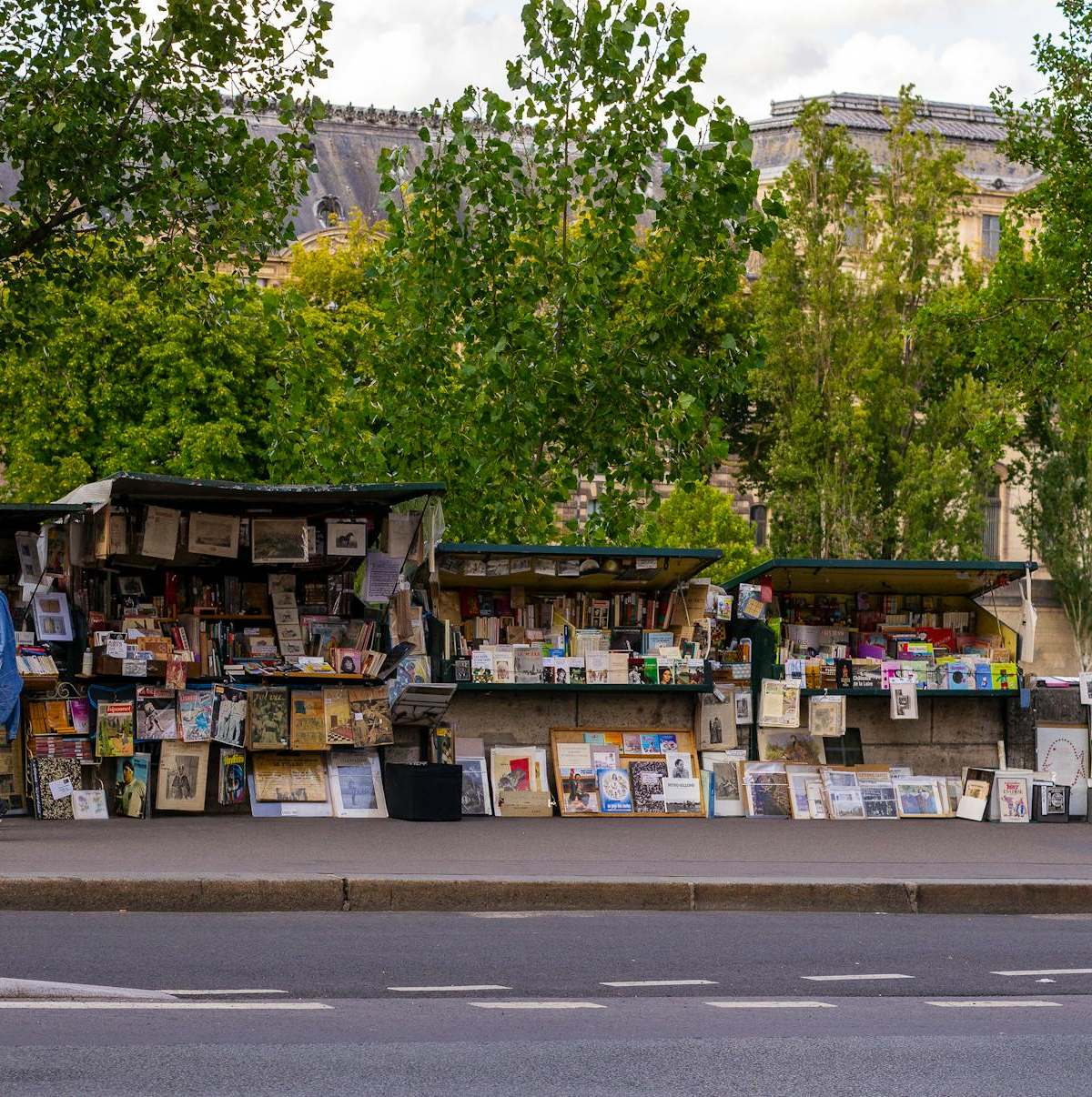Picturesque book stalls on a Paris street with people exploring in daylight.