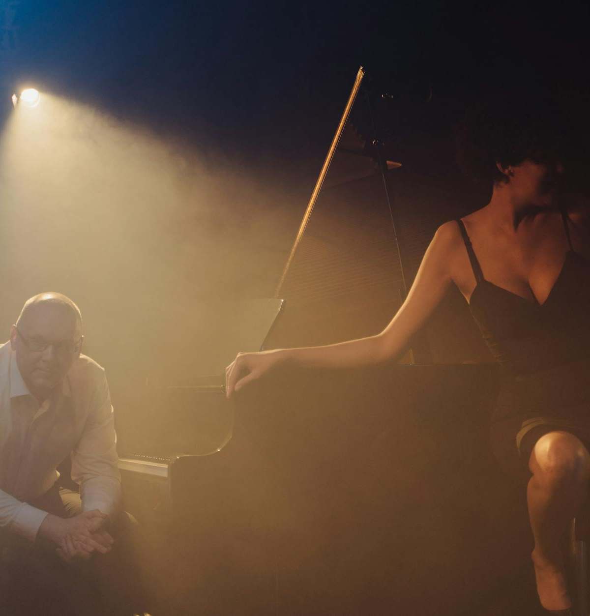 Moody jazz club performance featuring a pianist and singer on stage.