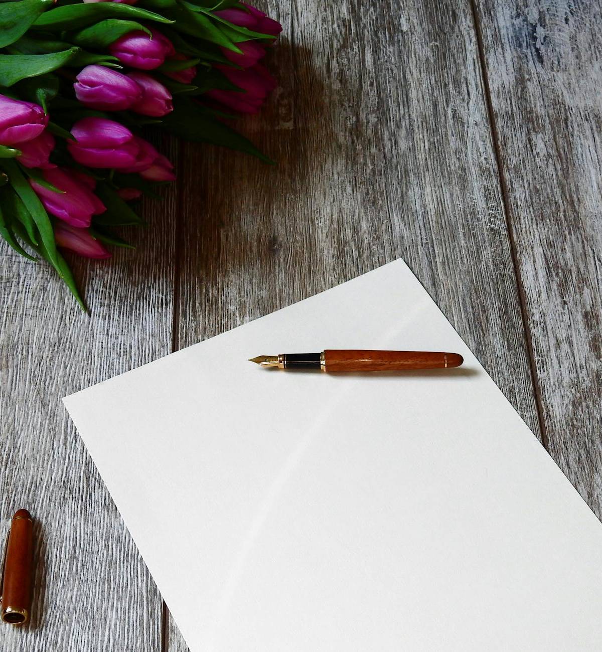 Paper, a pen and flowers on a writing table